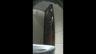 The camera pans to a close-up of a girls red-hot pussy as she spreads her legs wide and pees into the toilet
